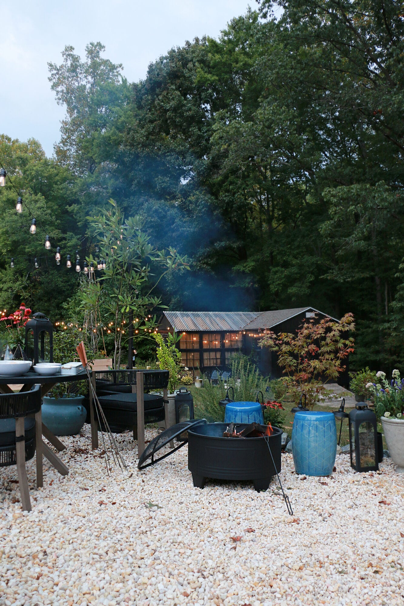 Fire pit in a gravel patio with a greenhouse in the background