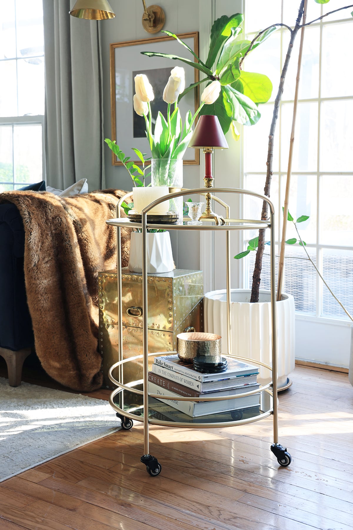 Gold bar cart holding a stack of books and other decorative accessories