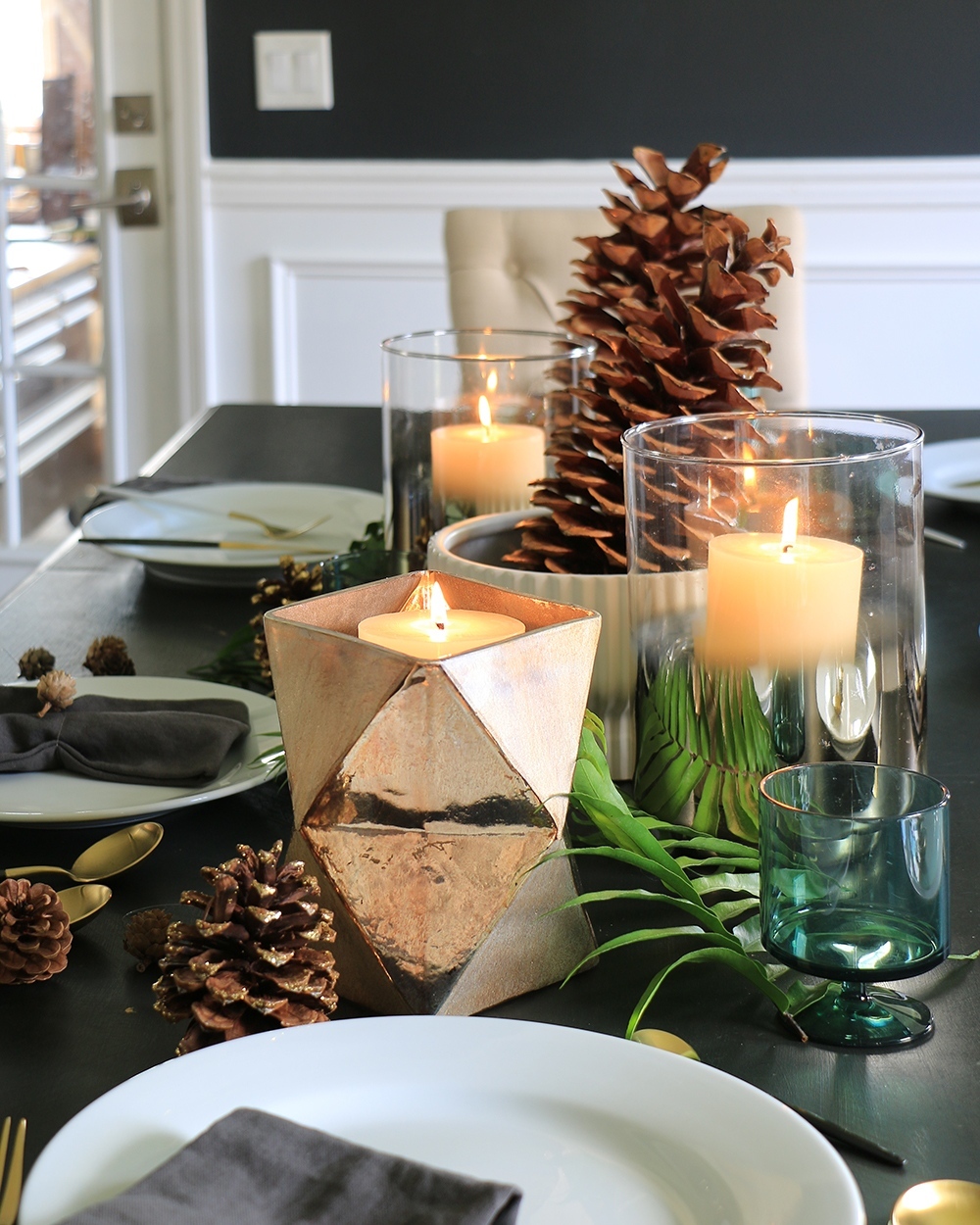 Fall dinner table with place settings, candles, pinecones, and foliage