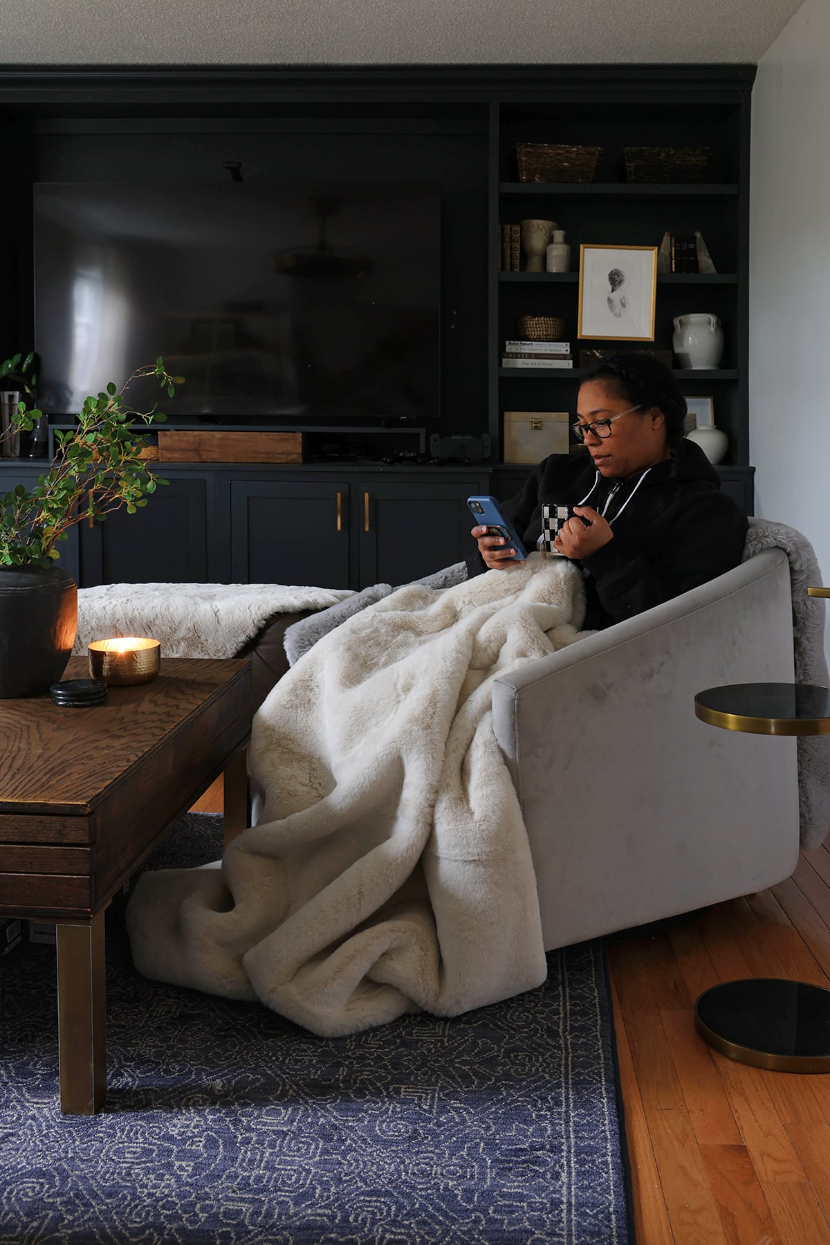 Ursula snuggled up with a blanket and hot drink in her cozy, modern living room