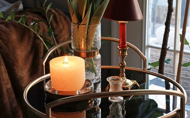 Cozy bar cart vignette with a lamp, plant, and candle