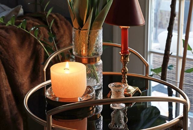 Cozy bar cart vignette with a lamp, plant, and candle