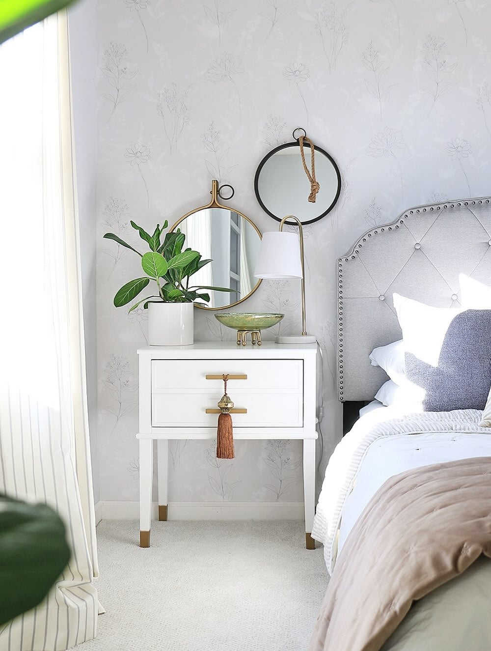 Bedside table vignette with a tassel hanging from a mirror