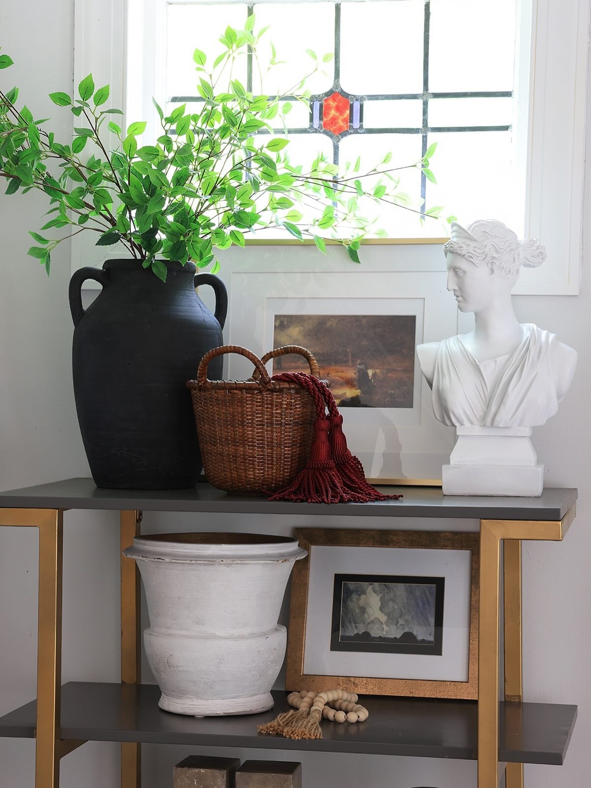 Shelf with various decorative items including a woven basket, decorated with a tassel